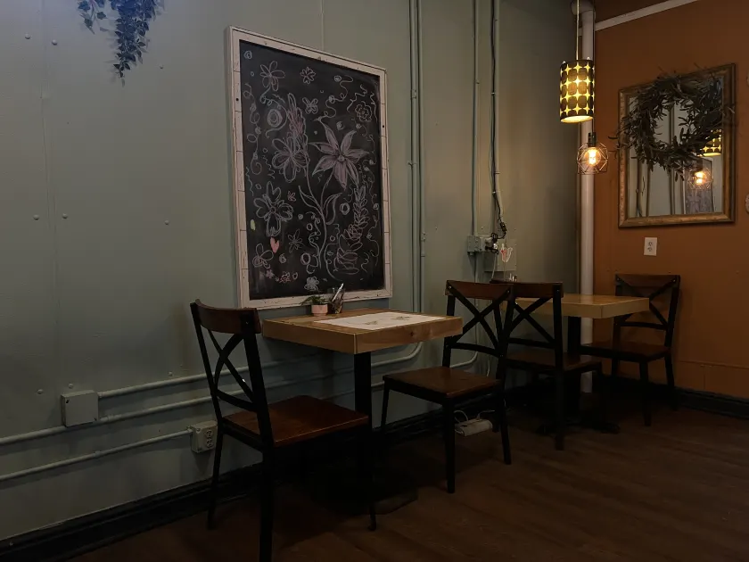Café tables and chairs beneath a floral chalkboard and warm pendant lights